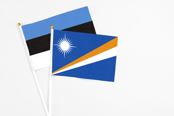 Marshall Islands and Estonia stick flags on white background. High quality fabric, miniature national flag. Peaceful global concept.White floor for copy space.