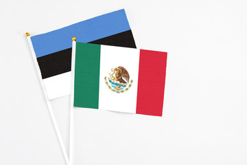 Mexico and Estonia stick flags on white background. High quality fabric, miniature national flag. Peaceful global concept.White floor for copy space.