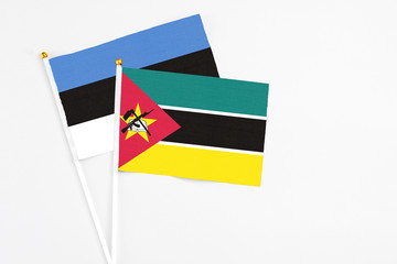 Mozambique and Estonia stick flags on white background. High quality fabric, miniature national flag. Peaceful global concept.White floor for copy space.