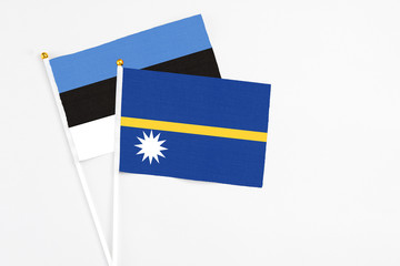 Nauru and Estonia stick flags on white background. High quality fabric, miniature national flag. Peaceful global concept.White floor for copy space.