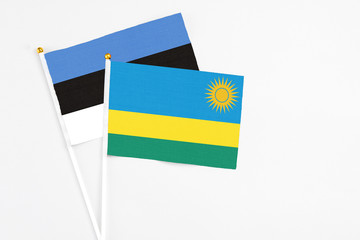 Rwanda and Estonia stick flags on white background. High quality fabric, miniature national flag. Peaceful global concept.White floor for copy space.