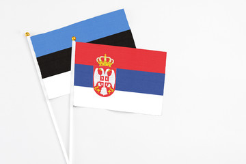 Serbia and Estonia stick flags on white background. High quality fabric, miniature national flag. Peaceful global concept.White floor for copy space.