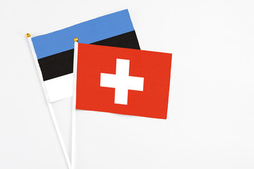 Switzerland and Estonia stick flags on white background. High quality fabric, miniature national flag. Peaceful global concept.White floor for copy space.