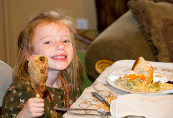 Little girl eating a turkey leg at thanksgiving