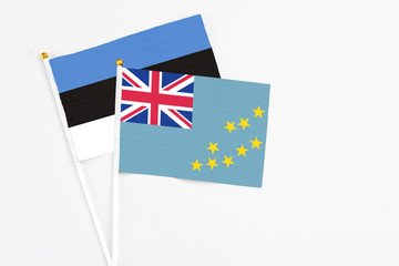 Fototapeta premium Tuvalu and Estonia stick flags on white background. High quality fabric, miniature national flag. Peaceful global concept.White floor for copy space.