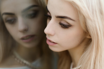 Portrait of a beautiful blonde girl. Reflection in the mirror.