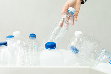 Closeup, hand of beautiful woman throw an empty single use plastic water bottle into sorting bin to separate from other recyclable materials. Waste separation and World environmental problem concept.