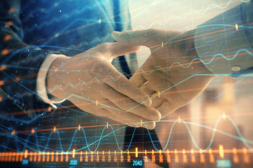 Double exposure of financial graph on cityscape background with two businessman handshake. Concept of stock market deal