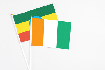 Cote D'Ivoire and Ethiopia stick flags on white background. High quality fabric, miniature national flag. Peaceful global concept.White floor for copy space.