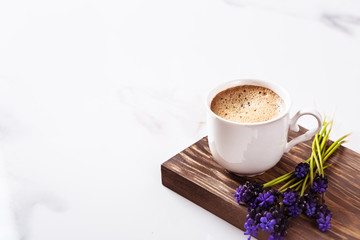 Obraz na płótnie Canvas Cup of fresh americano or espresso coffee with golden foam froth on pile of brown raw coffee beans on white marble table background. Morning hot drink, coffee break, cope space