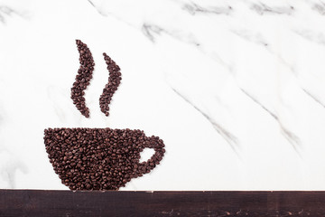 Coffee cup with steam made from roasted coffee beans or grain isolated on white marble background. Coffee shop concept