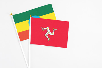 Isle Of Man and Ethiopia stick flags on white background. High quality fabric, miniature national flag. Peaceful global concept.White floor for copy space.