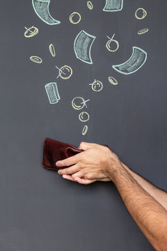 Concept of earning money with a brown leather wallet held in a hand in front of a blackboard with hand drawn coins and banknotes