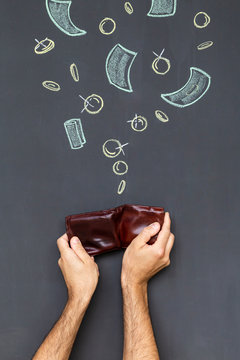 Concept of earning money with a brown leather wallet held in a hand in front of a blackboard with hand drawn coins and banknotes