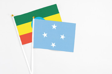 Micronesia and Ethiopia stick flags on white background. High quality fabric, miniature national flag. Peaceful global concept.White floor for copy space.