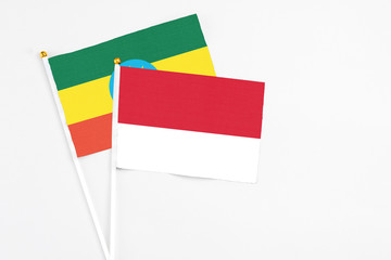 Monaco and Ethiopia stick flags on white background. High quality fabric, miniature national flag. Peaceful global concept.White floor for copy space.