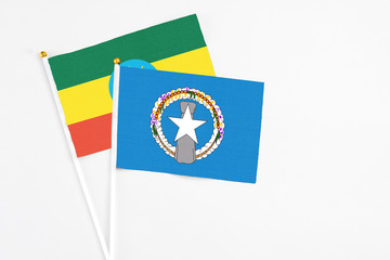 Northern Mariana Islands and Ethiopia stick flags on white background. High quality fabric, miniature national flag. Peaceful global concept.White floor for copy space.