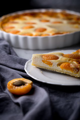 Apricot and cottage cheese pie or shortbread crust cake in white baking pan on dark grey washed linen table cloth, summer fruit dessert 