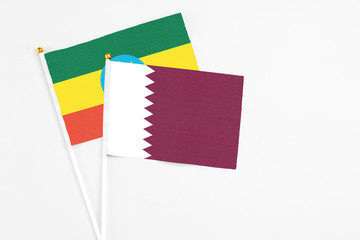 Qatar and Ethiopia stick flags on white background. High quality fabric, miniature national flag. Peaceful global concept.White floor for copy space.