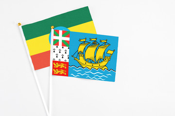 Saint Pierre And Miquelon and Ethiopia stick flags on white background. High quality fabric, miniature national flag. Peaceful global concept.White floor for copy space.