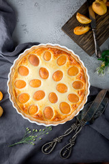 Apricot and cottage cheese pie or shortbread crust cake in white baking pan on dark grey washed linen table cloth, summer fruit dessert 