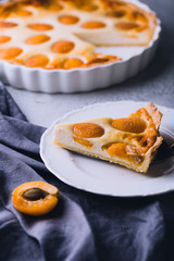 Apricot and cottage cheese pie or shortbread crust cake in white baking pan on dark grey washed linen table cloth, summer fruit dessert 