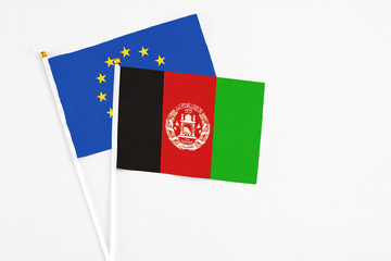 Afghanistan and European Union stick flags on white background. High quality fabric, miniature national flag. Peaceful global concept.White floor for copy space.