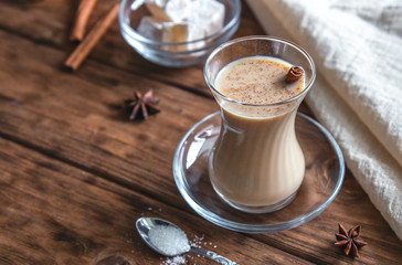 Indian tea with spices and milk on a wooden background. Masala chai