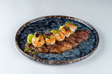 Flank steak with grilled prawns and herb sauce isolated on white background