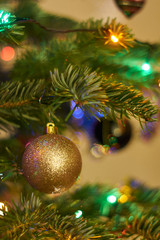 New Year's composition, Christmas decorations. Golden christmas ball hanging on a fir-tree against the background of a luminous Christmas garland