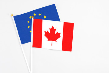 Canada and European Union stick flags on white background. High quality fabric, miniature national flag. Peaceful global concept.White floor for copy space.