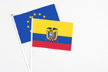 Ecuador and European Union stick flags on white background. High quality fabric, miniature national flag. Peaceful global concept.White floor for copy space.