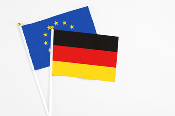 Germany and European Union stick flags on white background. High quality fabric, miniature national flag. Peaceful global concept.White floor for copy space.
