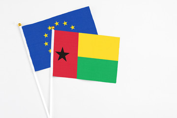 Guinea Bissau and European Union stick flags on white background. High quality fabric, miniature national flag. Peaceful global concept.White floor for copy space.