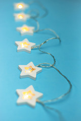 Christmas lights in the shape of stars on a blue background. New Year and Christmas concept, flat lay, top view