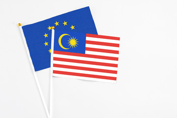 Malaysia and European Union stick flags on white background. High quality fabric, miniature national flag. Peaceful global concept.White floor for copy space.