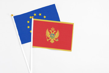 Montenegro and European Union stick flags on white background. High quality fabric, miniature national flag. Peaceful global concept.White floor for copy space.
