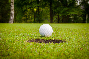 Golf ball on green meadow. golf ball on lip of cup