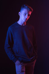 Naklejka premium Serious young guy in brown sweater in neon light