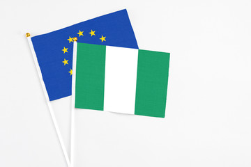 Nigeria and European Union stick flags on white background. High quality fabric, miniature national flag. Peaceful global concept.White floor for copy space.