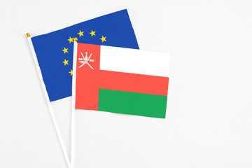 Oman and European Union stick flags on white background. High quality fabric, miniature national flag. Peaceful global concept.White floor for copy space.