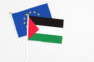 Palestine and European Union stick flags on white background. High quality fabric, miniature national flag. Peaceful global concept.White floor for copy space.