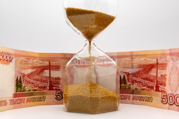 Hourglass and Russian banknotes on white background time money