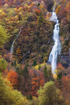 Waterfall in a colorful autumn forest in italy