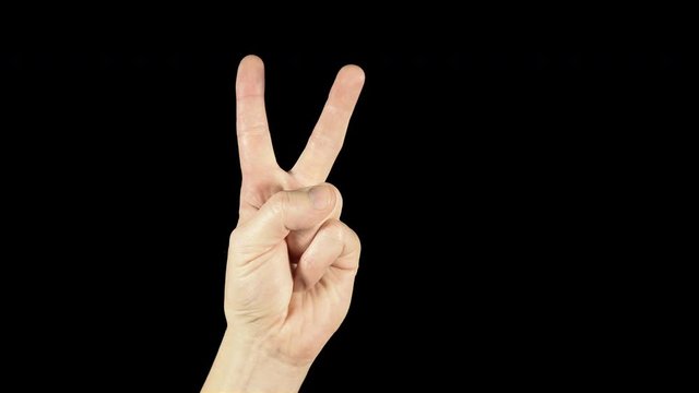 Two fingers on a hand raised up as a symbol of victory. A popular and famous hand gesture on a black isolated background. Gesture two fingers in a badge of world.