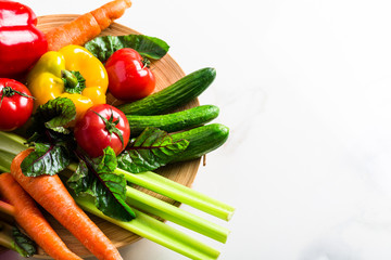 Mix of assorted fresh raw organic vegetables and greens in bowls for spring and summer dieting salad on white kitchen marble background. Healthy eating flat lay concept, copy space