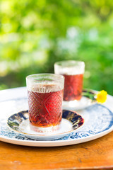Two crystal glasses of black tea with saucers in garden, Novruz or Ramadan celebration, copy space