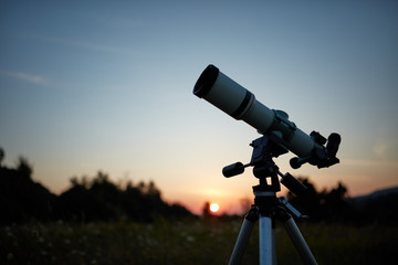 Telescope for observing the universe on a meadow outdoors.