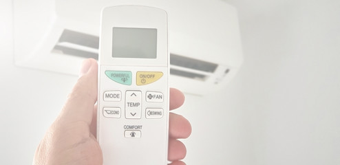 Modern airconditioner unit with a hand holding a remote.