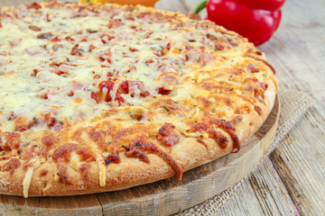 whole pizza with ham and mozzarella on a wooden table